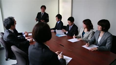 Japanese Business People Having A Meeting Around A Wooden Desk In A