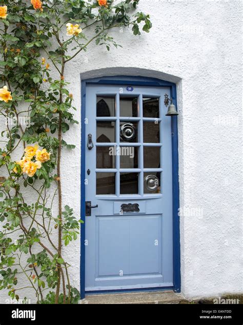Pale Blue Cottage Door With Gleaming Glass Surrounded By White Walls