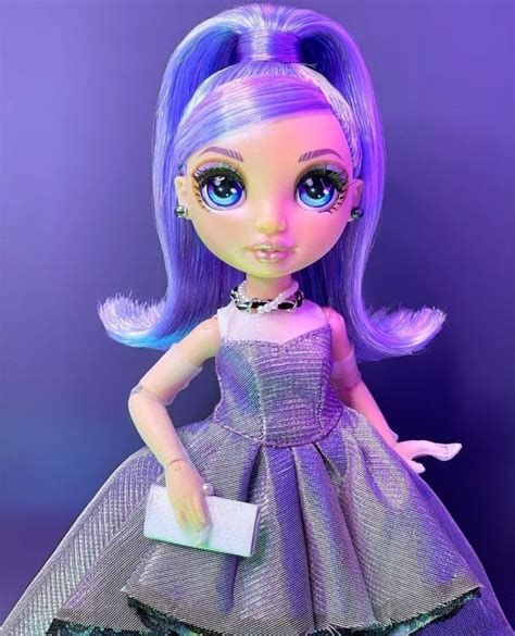A Doll With Purple Hair And Blue Eyes Is Wearing A Dress That Has