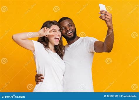 Um Casal Interracial Animado A Fazer Selfie Com Smartphone Divertindo Se Juntos Imagem De Stock