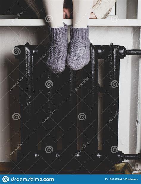 Girl Sits On A Windowsill Put Their Feet In Woolen Socks On The