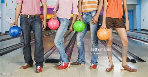 Two Young Couples Holding Bowling Balls In A Bowling Alley High Res