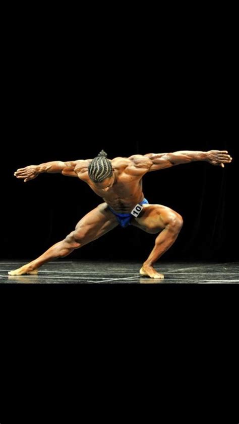 A Bodybuilding Man Doing A Handstand On The Floor In Front Of A Black