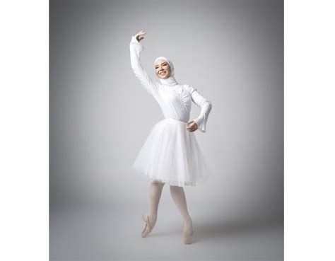 A Woman In A White Dress And Head Scarf Is Dancing With Her Arms Up
