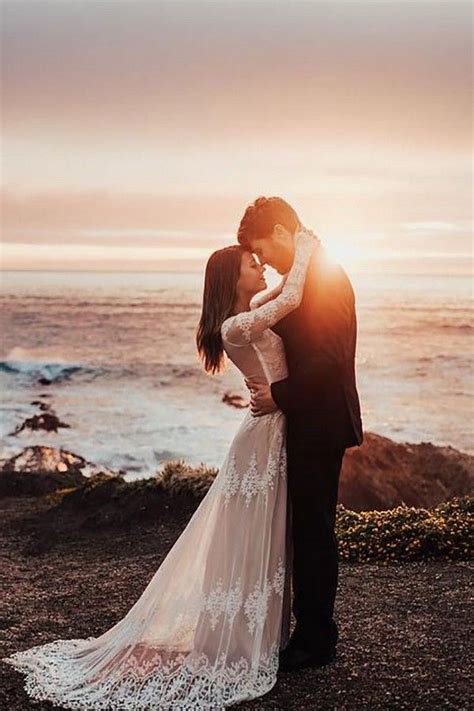 A Bride And Groom Kissing In Front Of The Ocean At Sunset On Their