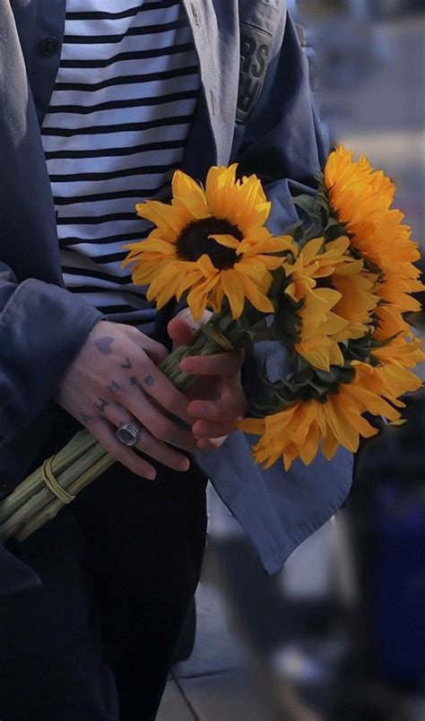 A Woman Holding A Bouquet Of Sunflowers In Her Hands