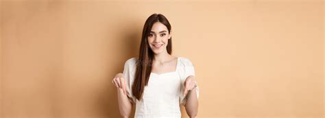Cheerful Young Girl With Lovely Smile Pointing Fingers Down Making