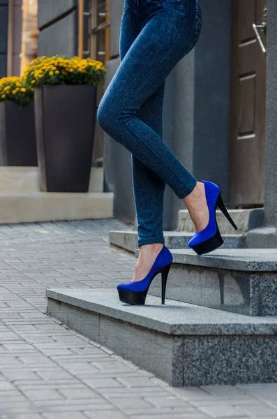Beautiful Slender Female Legs In Tight Jeans And Blue Shoes On A Stock