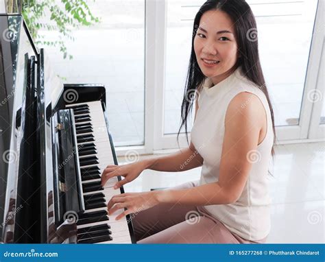 Asian Young Woman Playing Piano Upright In The White Room Stock
