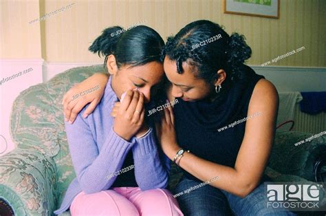 Teenage Girl Sitting On Sofa Crying Being Comforted By Older Sister