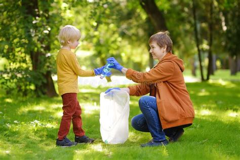Woman Volunteer And Little Boy Picking Up The Plastic Garbage And