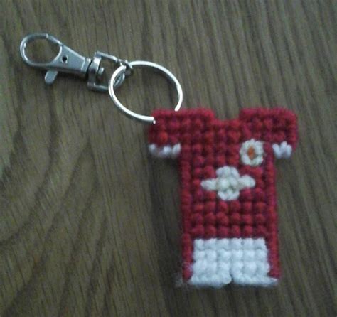 A Red And White Cross Stitch Keychain On A Wooden Table