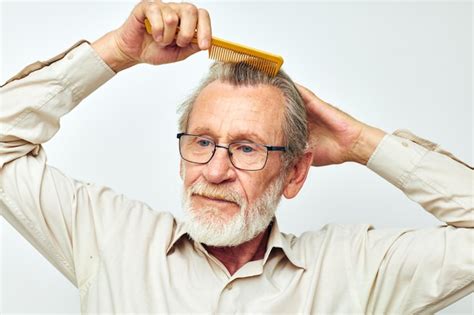 Homem idoso penteando o cabelo em estúdio Foto Premium