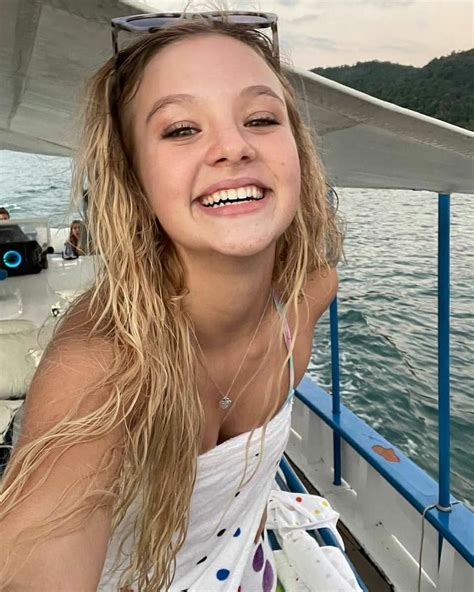 A Girl With Long Hair And Sunglasses On A Boat In The Water Smiling At