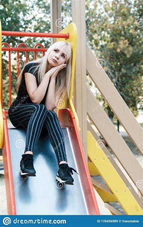 Sad Blonde Girl On Slide In Park On Blurred Background Stock Image