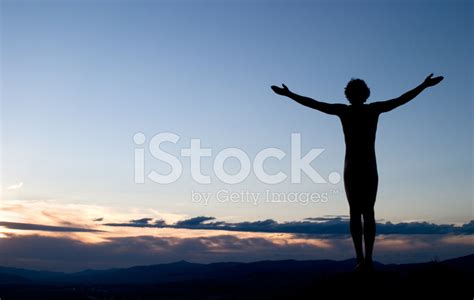 Silhouette Of Man With Arms Outstretched Towards Sky At Sunset Stock