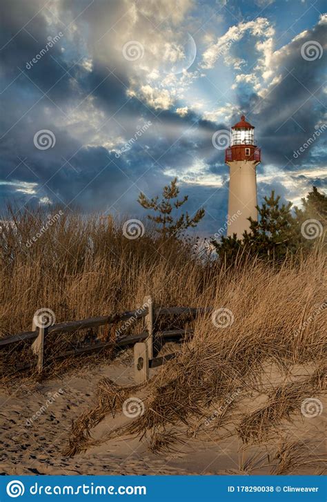 Lighthouse Shining Its Light Along The Seashore Under Cloudy Skies