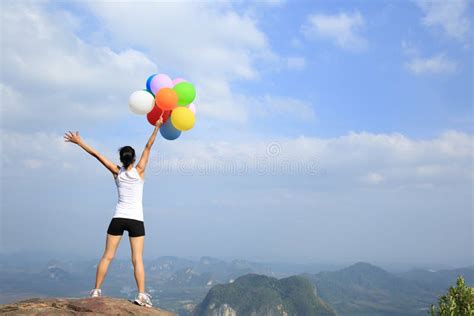 Woman Cheering On Mountain Peak With Colorful Balloons Stock Photo