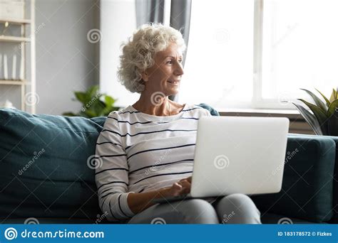 Dreamy Senior Mature Granny Resting With Laptop On Comfortable Sofa