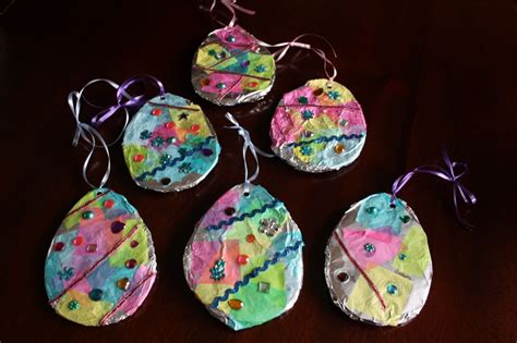 Four Handmade Easter Egg Ornaments On A Table With Purple Ribbon Around