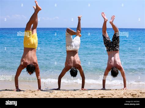 Three Young Men Doing Handstands On Beach Stock Photo Alamy