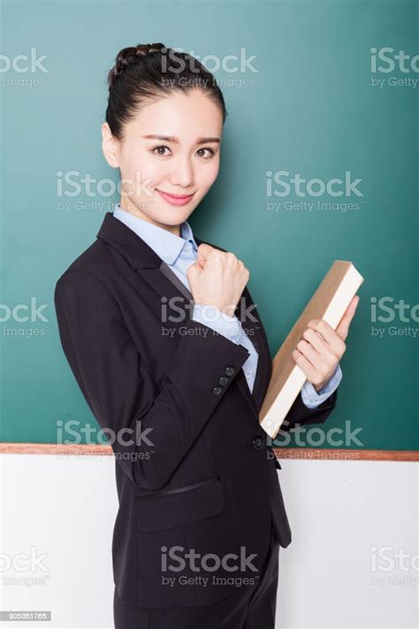 Female Teacher Holding Book Front Of Blackboard Stock Photo Download