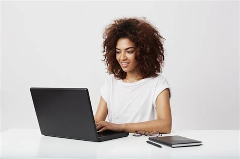 Free Photo African Businesswoman Smiling Working At Laptop Over White Wall