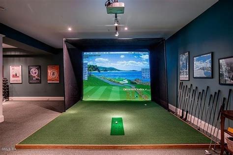 An Indoor Golf Simulator Is Set Up In A Room With Several Pictures On