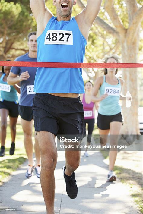 Male Runner Crossing Red Tape Arms Raised Winning Marathon Stock Photo