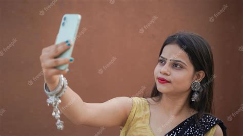 premium photo beautiful indian girl taking selfie on her mobile phone outdoor cheerful asian