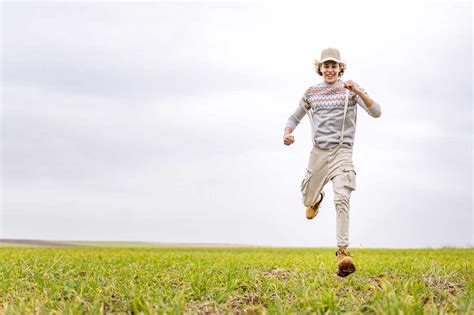 Young Man Running Toward Camera Across Grassy Field Stock Photo
