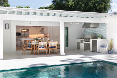 An Outdoor Kitchen And Dining Area Next To A Swimming Pool In A Home