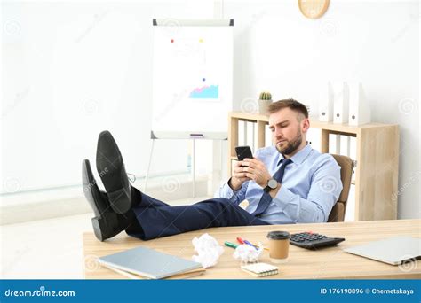 Lazy Office Employee With Mobile Phone At Workplace Stock Photo Image