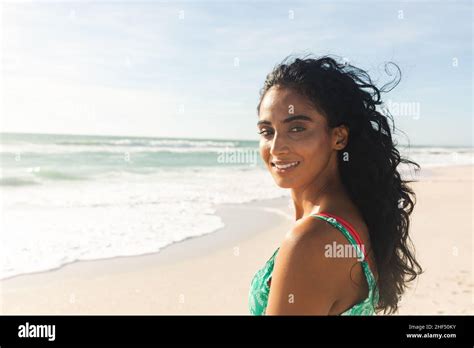 Portrait Of Smiling Beautiful Young Biracial Woman Looking Over Shoulder At Beach Enjoying Sunny