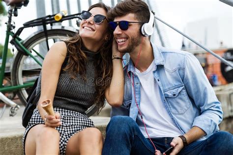 Happy Young Couple Listening To Music In The Street Stock Photo