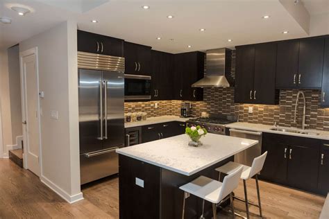 Light hardwood flooring and dark wooden cabinetry compliment each other in this kitchen featuring light tile backsplash and hidden lighting. 52 Dark Kitchens with Dark Wood and Black Kitchen Cabinets