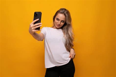 girl takes a selfie on the phone on a yellow background stock image image of mobile