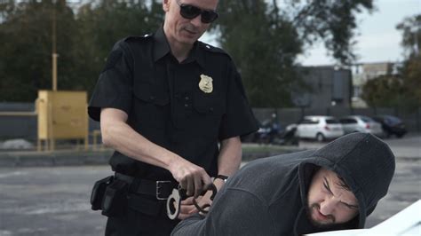 Police Officer Arresting Criminal Putting Him On Car Trunk And Reading