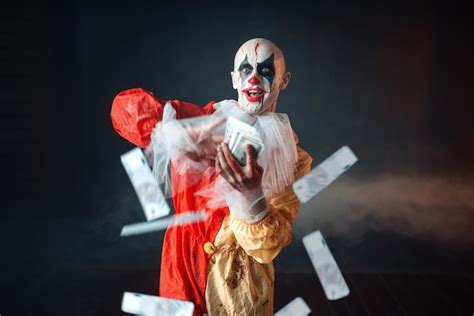 Premium Photo Scary Bloody Clown With Crazy Eyes Holds Fan Of Money