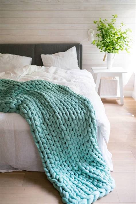 The child's hands hold a knitted blanket. Cozy throw blanket from wool yarn in lagoon green color ...
