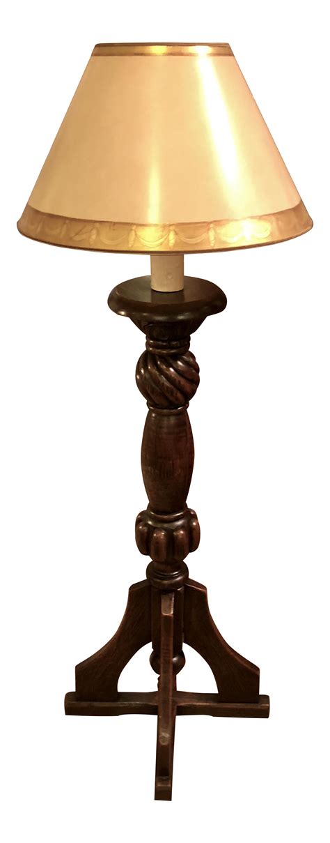 A Lamp That Is On Top Of A Wooden Stand With A Beige Shade Over It