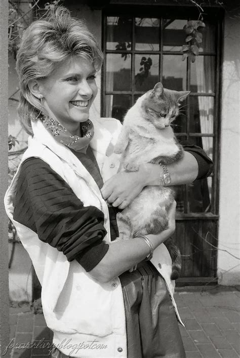 A Woman Is Holding A Cat In Her Arms And Smiling At The Camera While