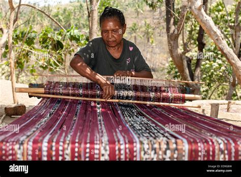 Indonesian Woman Weaving Traditional Sarongs On The Roadside On The