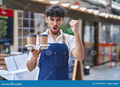 arab man with beard wearing waiter apron at restaurant terrace annoyed and frustrated shouting