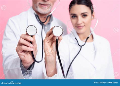 Portrait Of Smiling Male And Female Doctors Holding Stethoscopes To