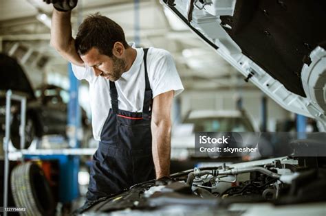 Overworked Sweaty Repairman Examining Car Problems In A Workshop Stock