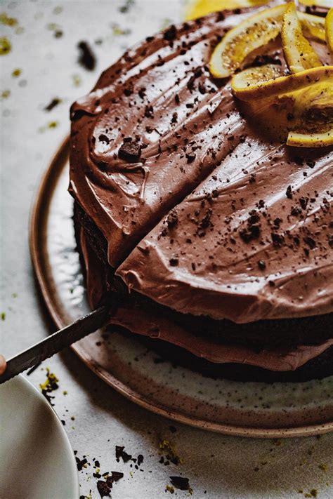 Contemporary chocolate mini mousse cake made in heart shape silicone mold, covered with brick color velvet spray and decorated with blood orange caviar, on black background. Chocolate Orange Cake | Olive & Mango