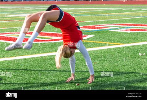 A High School Cheerleader Warming Up Doing Back Flips On A Turf Field Before The Game Stock
