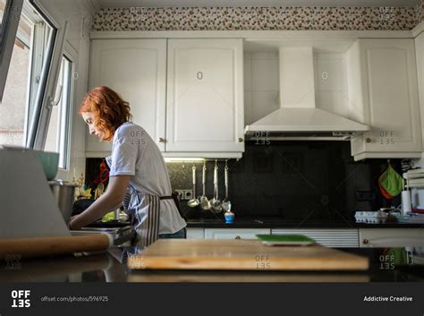Side View Of Babe Woman Washing Dishes In A Sink In The Kitchen
