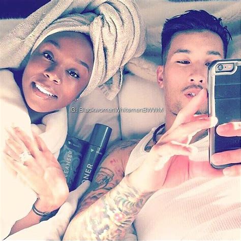 A Man And Woman Laying In Bed Taking A Selfie With Their Cell Phones